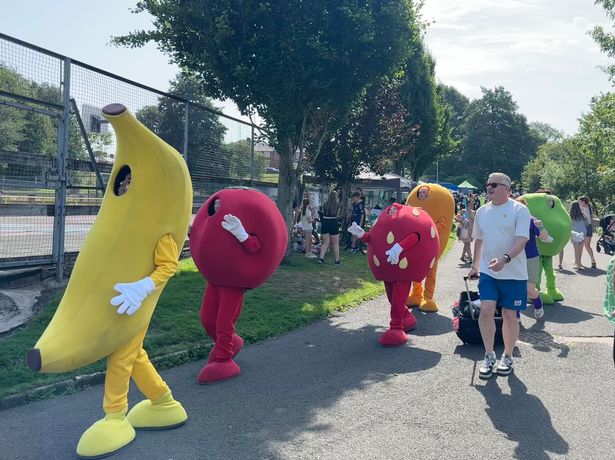  A gaggle of dancers in giant fruit costumes, unperturbed by the sweltering heat, whisk the youngsters into energetic dance routines.