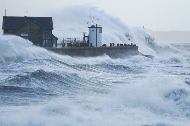 sea crashing against harbour and lighthouse