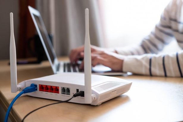 Selective focus at router. Internet router on working table with blurred man connect the cable at the background. Fast and high speed internet connection from fiber line with LAN cable connection.