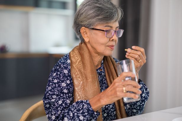 A picture of an old lady taking medicine