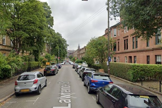 An image of a street lined with red-brick buildings and leafy trees.