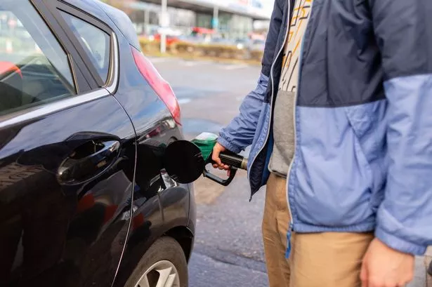Man's hand holding petrol pump and filling car close up