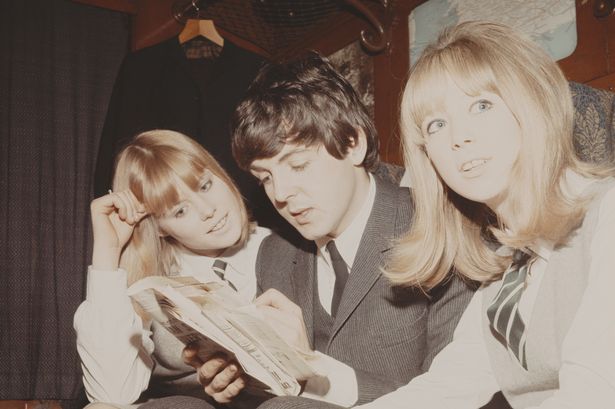Paul McCartney completes a crossword puzzle with Patti Boyd (right) and another extra on a train from Marylebone Station during the filming of 'A Hard Day's Night'