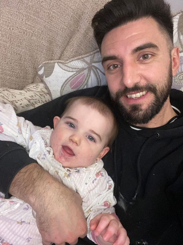 A man holding a baby girl and smiling at the camera