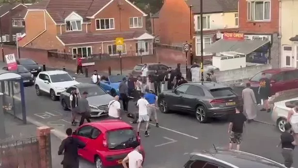 A huge fight broke out in broad daylight on a residential street in Birmingham last week and was captured on film, with a man brandishing a large knife attempting to slash two men during the melee