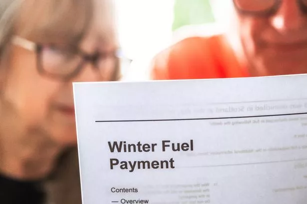 A senior married couple in their 70s study documents relating to winter fuel payments for pensioners while sitting down in their living room at home. The winter fuel payments were introduced by the British government to help people during the cost of living crisis. The couple have serious, worried expressions as they study the information.