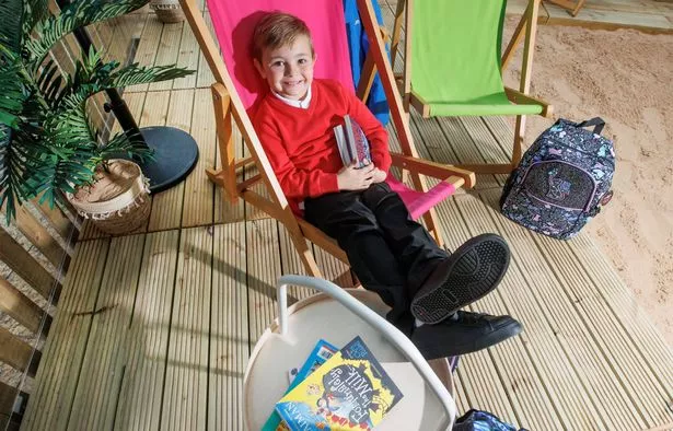 Boy sitting on chair smiling with books