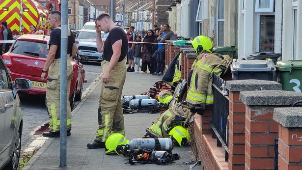 Firefighters in a residential street with breathing apparatus on the floor near them