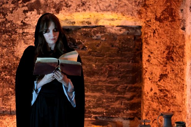 Female actor in old dress with a book open in the Close