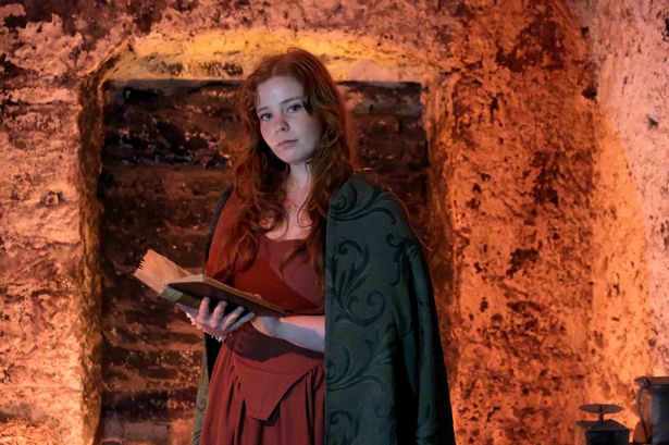 Female actor in old dress with a book open in the Close