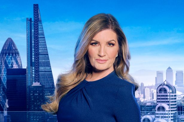 Karren Brady in a blue dress, with a skyline visible behind her, in a promo photo for the Apprentice.