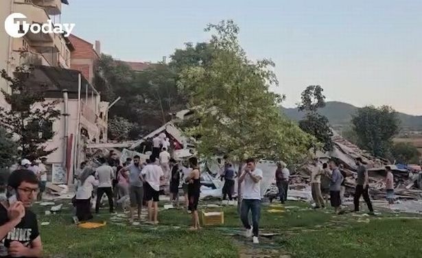 Locals stand outside a collapsed building 