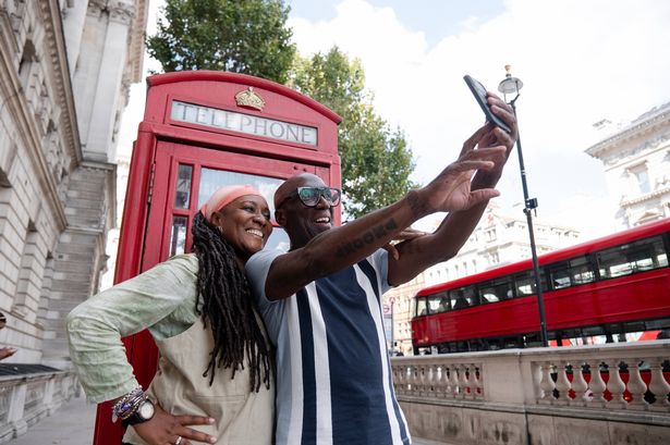 UK, London, Happy mature couple taking selfie in front of traditional red telephone booth