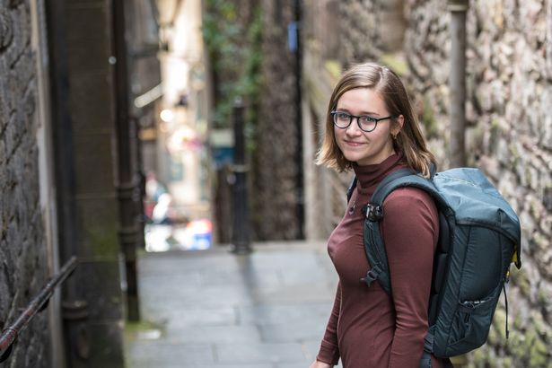 UK, Scotland, Edinburgh - A young female tourist poses in an alleyway in Edinburgh, Scotland