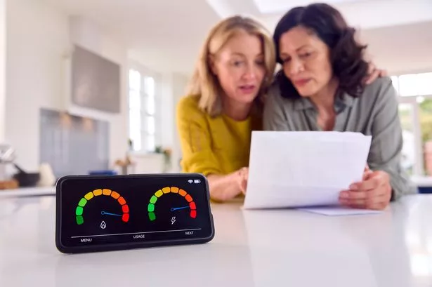 Two people looking At Bills With Energy Meter In Foreground