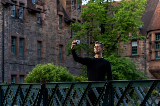 Young man takes photo on a green bridge in Edinburgh 