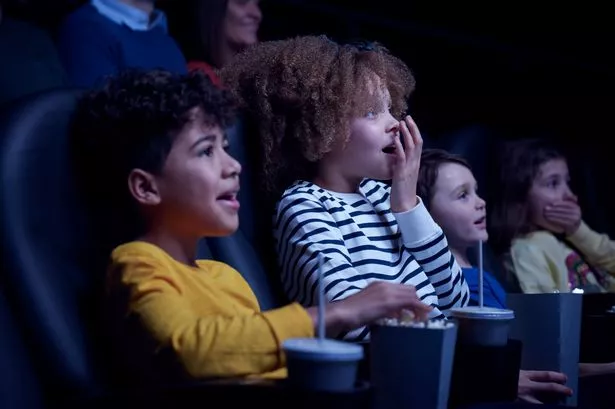 Children eating popcorn and watching movie in cinema