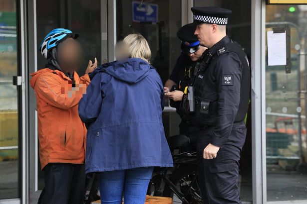 Police and Home Office workers speak to delivery riders in Ashton, Tameside