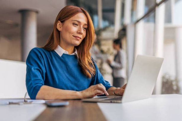 Young woman working at a desktop using laptop