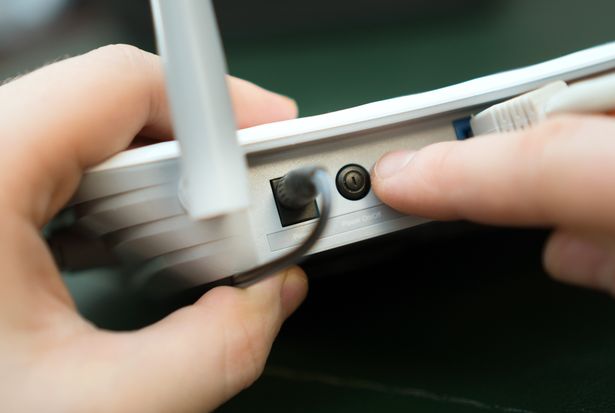 Man pressing power button on the WiFi router