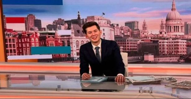 GMB presenter Will Godley behind the news desk smiling