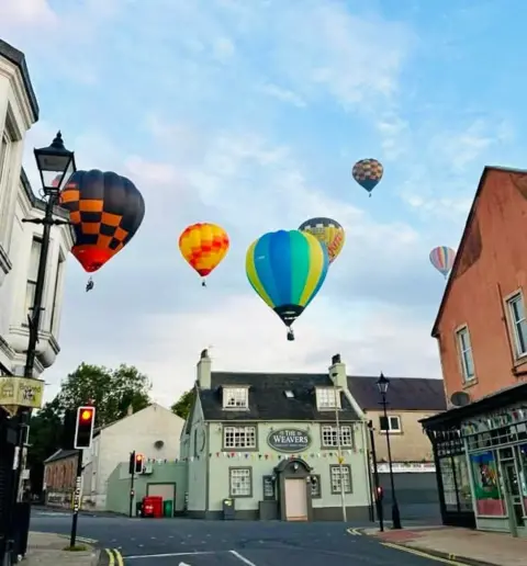 Julie Morrison Brightly coloured hot air balloons float above the Weavers pub, which is an idyllic mint green building with coloured bunting.