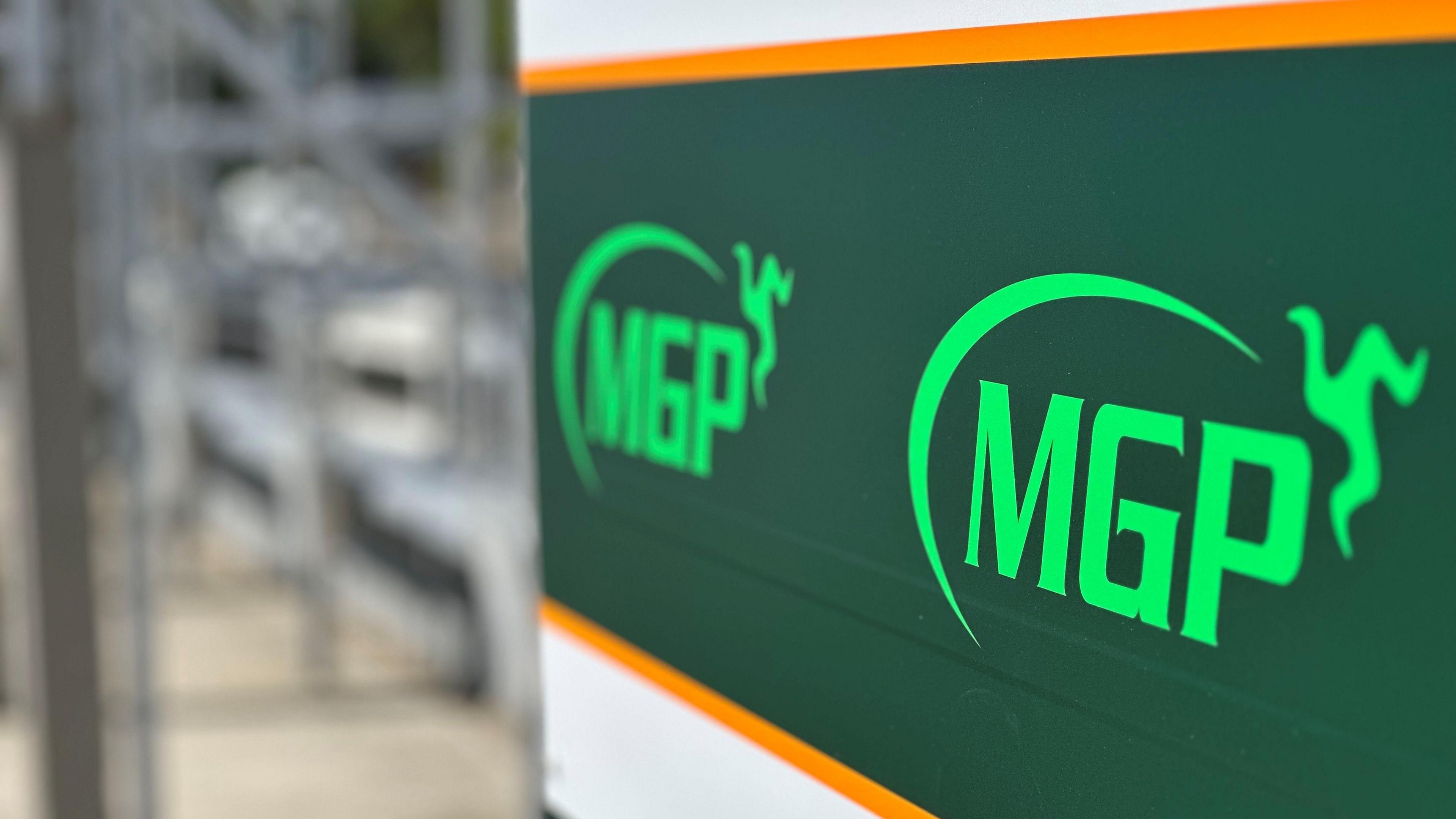 A sign in the pitlane at the grandstand featuring the MGP logo, which includes a semi-circle with a three legs of Mann emblem at one end.