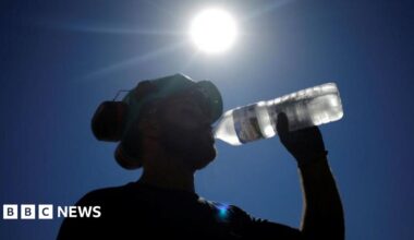 Labourers wearing hi-viz orange tops drink water to cool down as they work on a construction site of tramway lines along the Garonne river in France