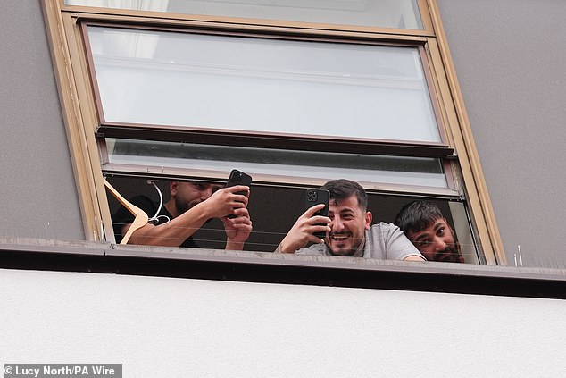 People believed to be migrants have been seen filming and laughing from a window at the Thistle City Barbican Hotel in London