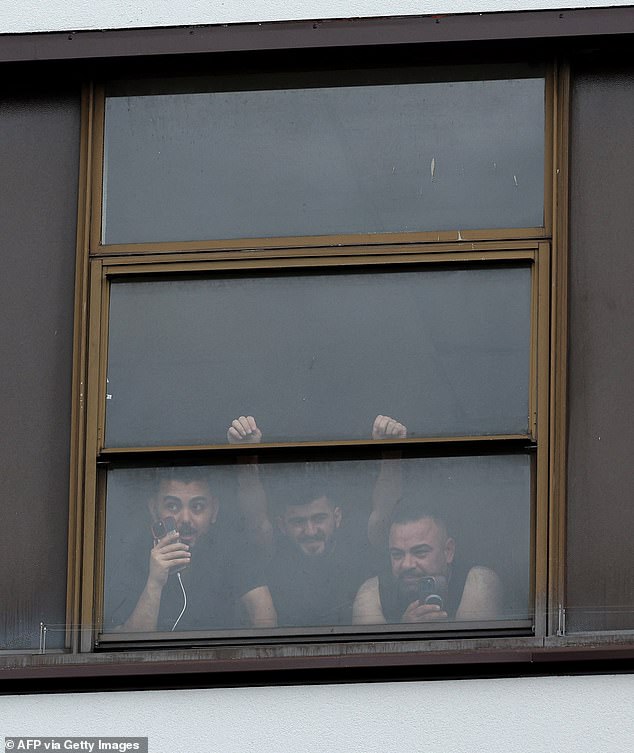 People look out from the Thistle City Barbican Hotel, which is believed to be housing asylum seekers