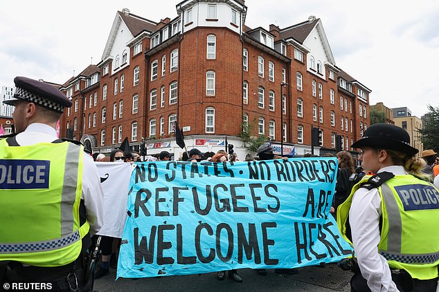 Counter demonstrators hold up a sign which reads: 'No states, no borders. Refugees are welcome here'