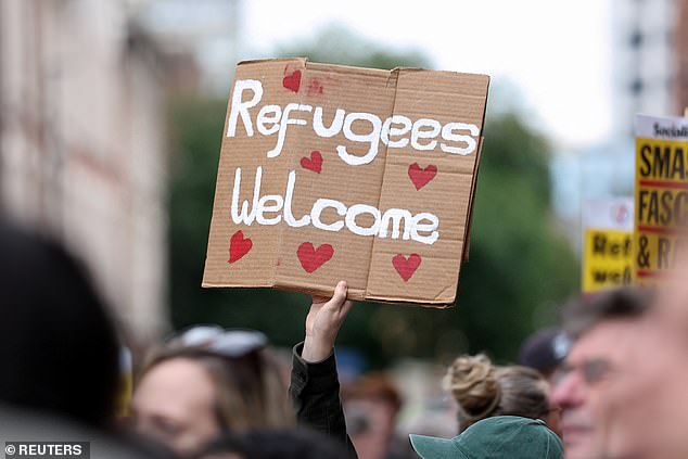 A counter protester holds a sign which reads: 'Refugees welcome'