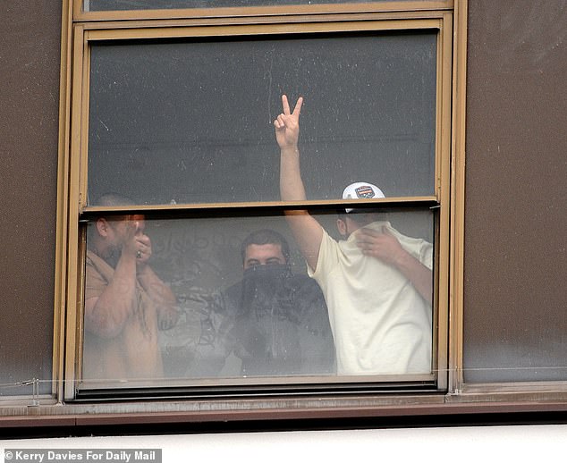 One man could be seen doing a peace sign from inside the hotel believed to be housing migrants
