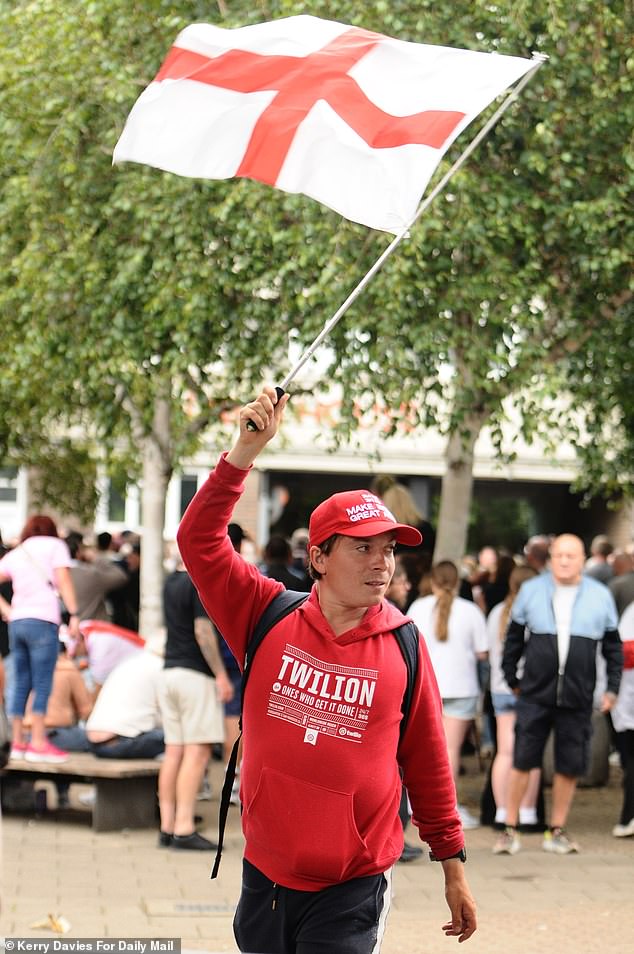 A man waves a St George flag as protests surrounding a hotel believed to be housing  migrants continues in north London today
