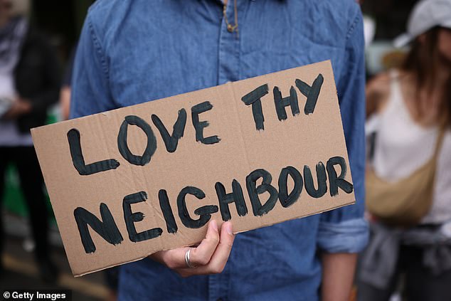Another counter demonstrator holds up a sign which reads: 'Love thy neighbour'