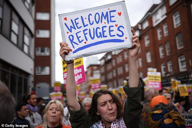 Counter protesters from Stand Up To Racism gather outside the Barbican Thistle, one with a sign that reads 'Welcome refugees'
