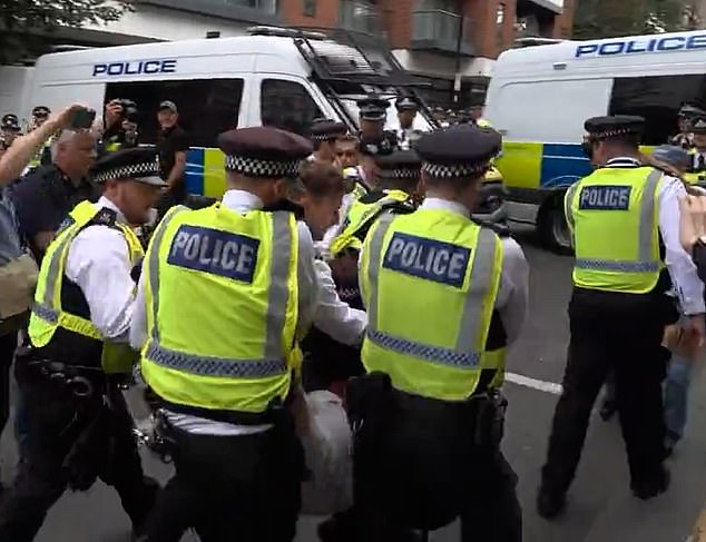 Police are seen carrying a protester  by their arms and legs amid the demonstration today