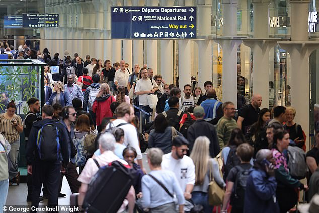 Passengers wait for trains in a busy London St Pancras international station today