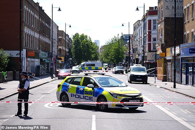 Police officers patrol at a cordon on Stoke Newington High Street