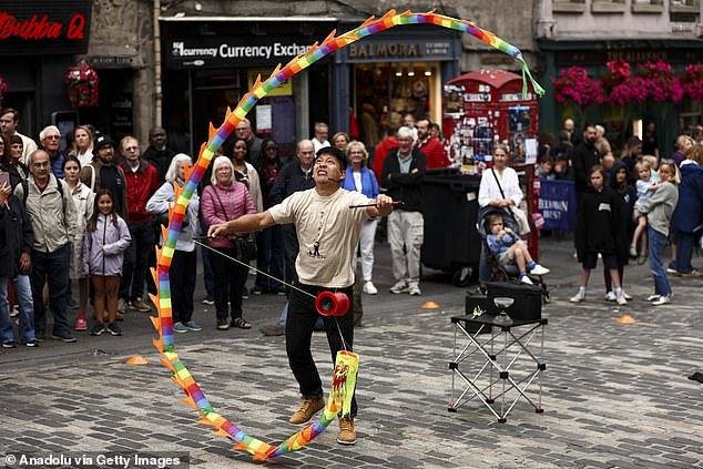A street performer entertains passersby on the Royal Mile as crowds of entertainers and festivalgoers gathered for the opening day of the Edinburgh Festival Fringe