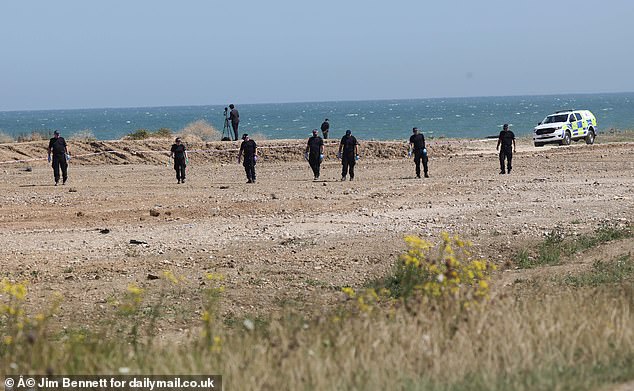A group of police officers pictured combing an area of the beach in Leysdown-on-Sea