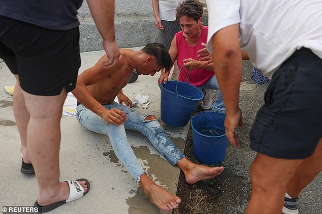 A man is assisted by residents after brething smoke, while they wait for help from emergency services in Vilar de Condes, in the province of Ourense in Galicia, Spain, August 15