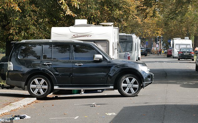 A black SUV is seen parked perpendicular to the curb along Warwick Road in Ealing