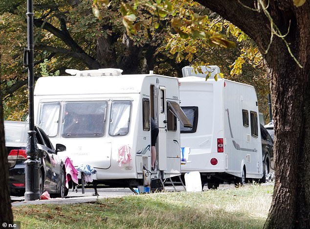 Two large caravans are seen parked along the road going through Ealing Common in West London