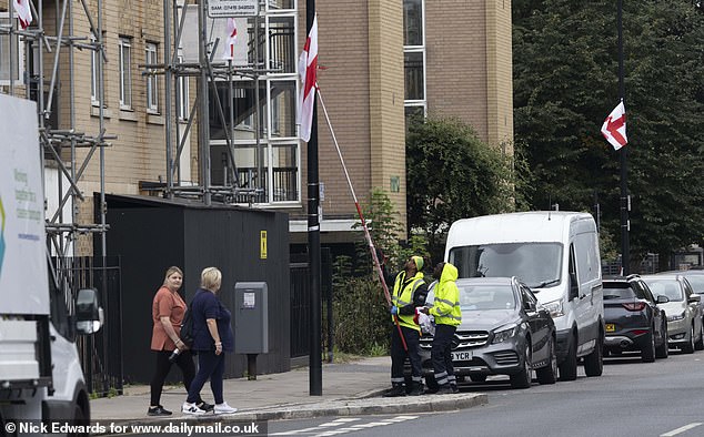 Tower Hamlets council workers pull down a St George's Cross put up by patriotic campaigners