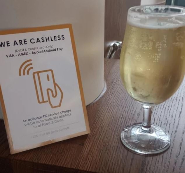 A London pub has now added a four per cent 'optional charge' to any drinks customers order at the bar. Pictured: Sign advertising the bar service charge in the pub