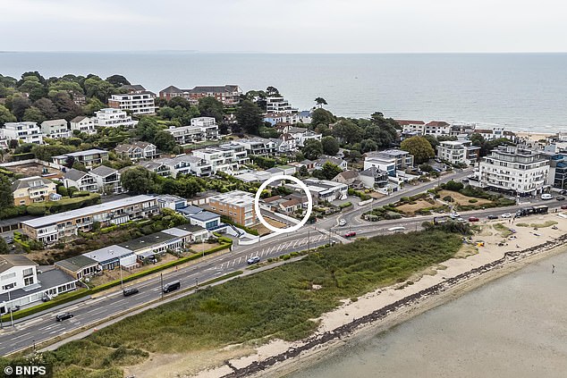 The tiny house sits on the edge of Poole Harbour and has views of millionaire's playground Sandbanks - but is dwarfed by properties around it