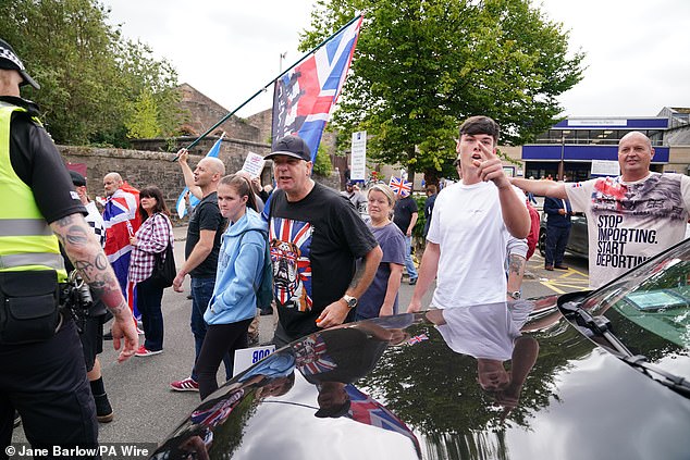 Anti-immigration protesters gesture towards counter-activists in Perth while dressed in Union Jacks
