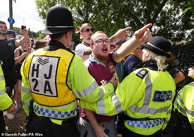 Police across Britain are out on the streets in force to police the protests and keep opposing groups separated. Pictured: People take part in a counter protest to a Stand Up To Racism rally outside the Sheraton Four Points Hotel in Horley, Surrey