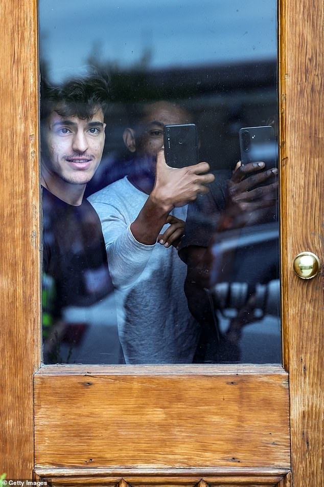 In Perth, asylum seekers watch and photograph the protests from inside the Radisson Hotel